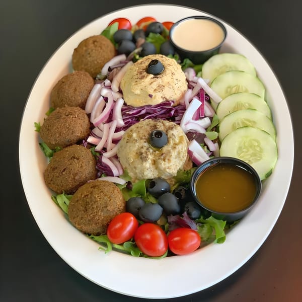A Mediterranean falafel salad with hummus, cucumbers, tomatoes, olives, and red onions.