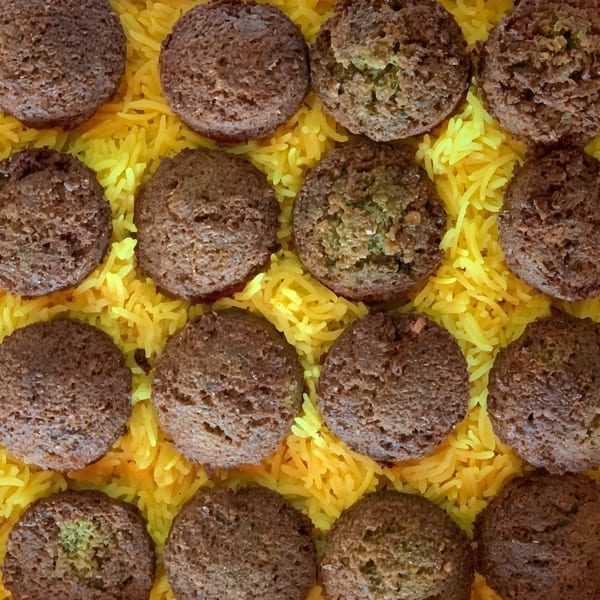 Twelve Olive Falafel falafel balls arranged on a bed of bright yellow rice.